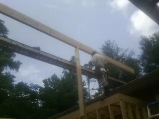 Carpenter setting a ridge beam over a new addition frame — Ice Dam Removal by Roofing Brothers in West Liberty
