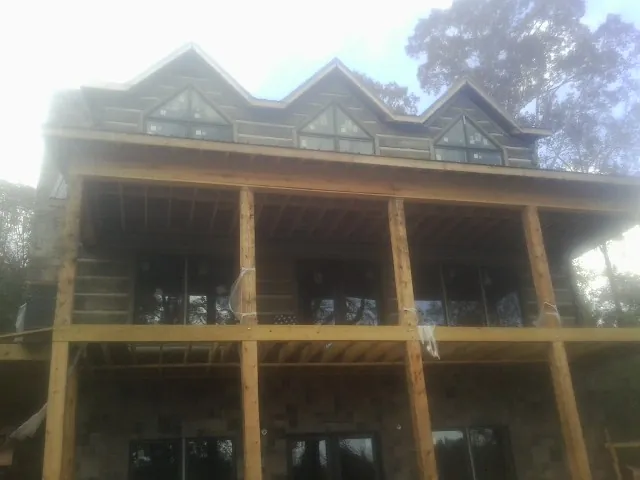 Dormers and porch framing on a large log home under construction — Roof Coating work by our crew in West Liberty