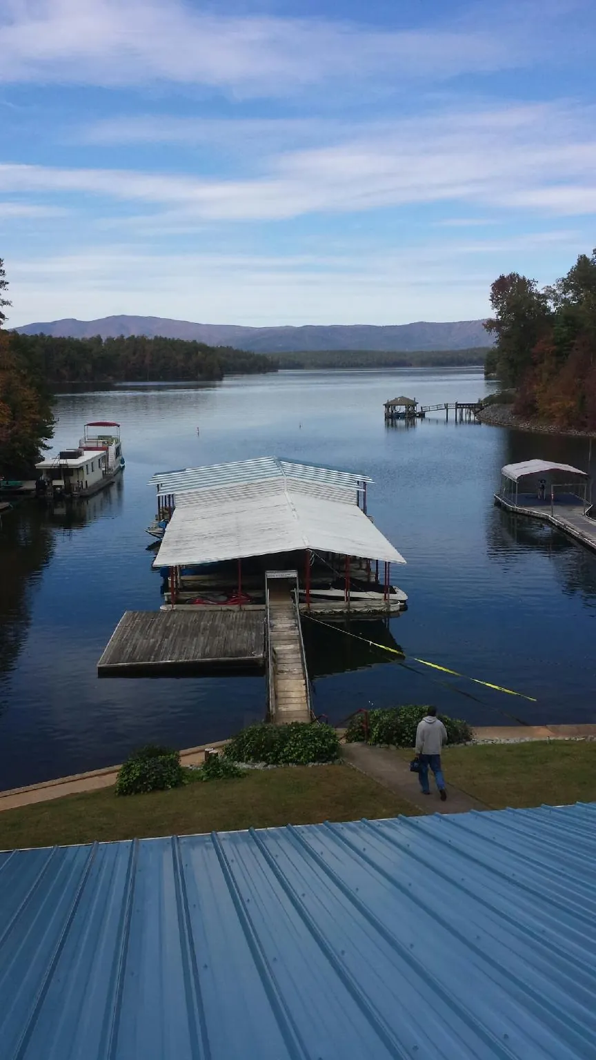View across a lake from a newly installed blue metal roof in West Liberty