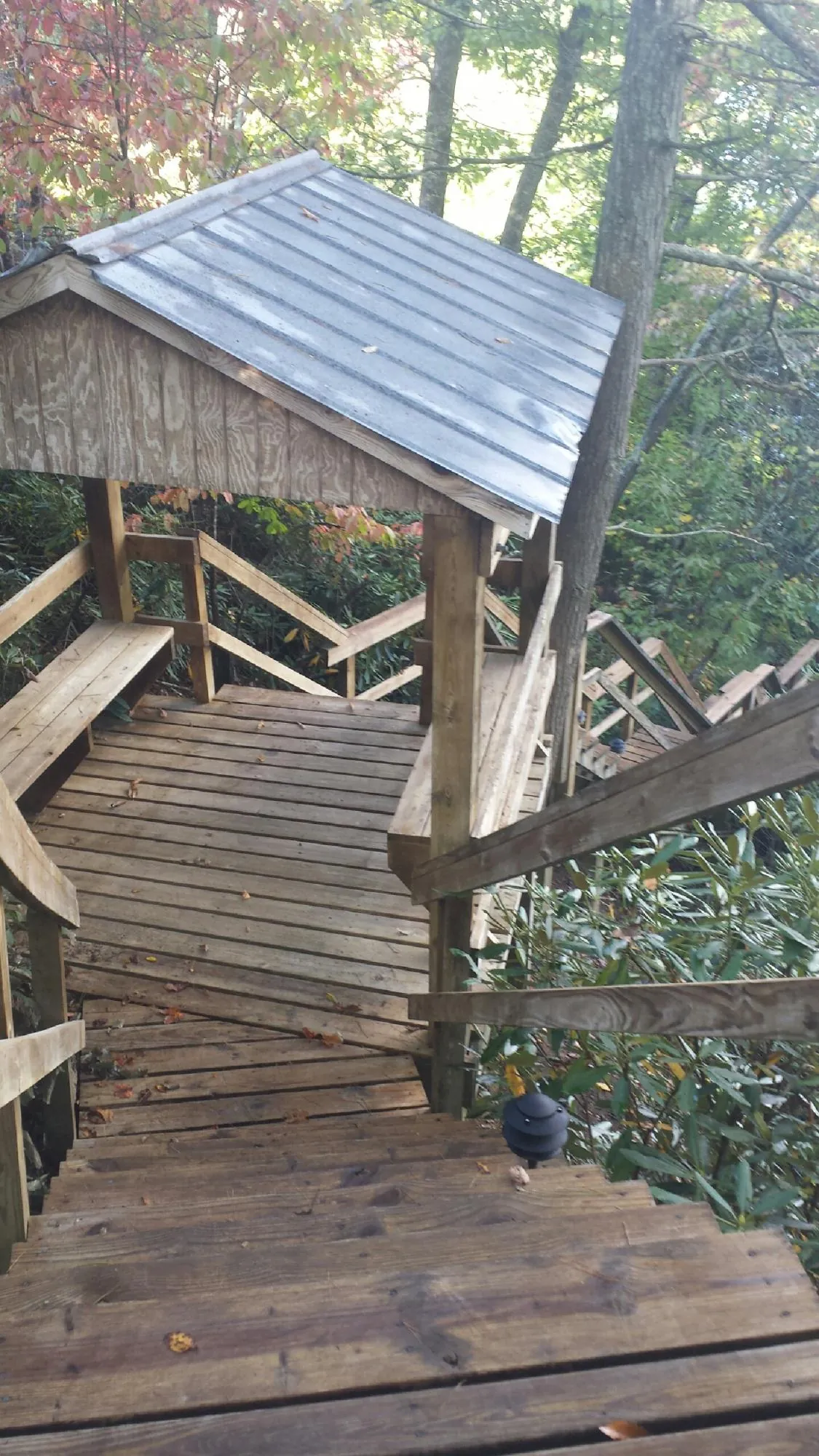 Metal roofed shelter over wooden steps on a wooded walkway — Skylight Repair & Installation work by our crew in West Liberty