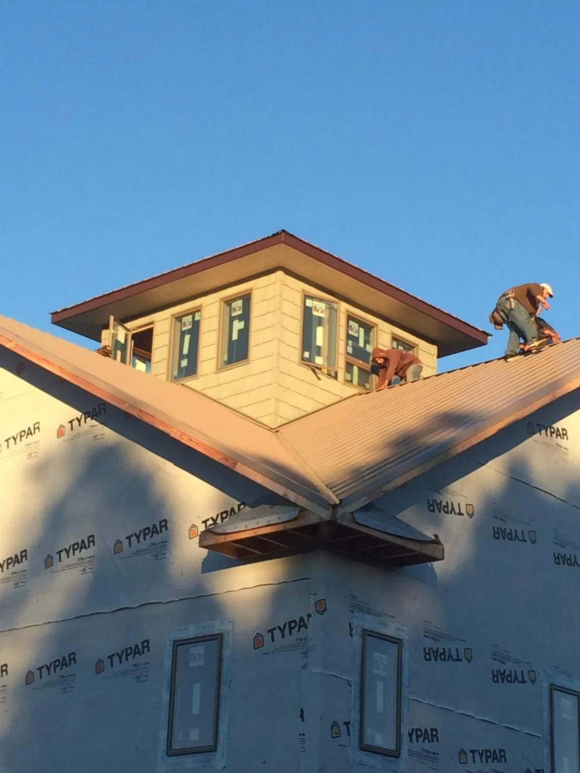 Roofers working around a rooftop cupola on a new metal roof at sunset — Roof Waterproofing in West Liberty by Roofing Brothers
